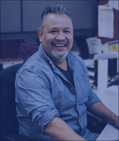 Picture. An Employee sitting at their desk smiling.