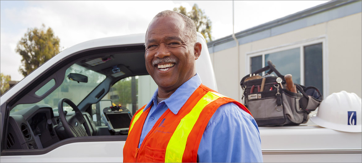 Picture. An employee standing in front of their truck smiling.