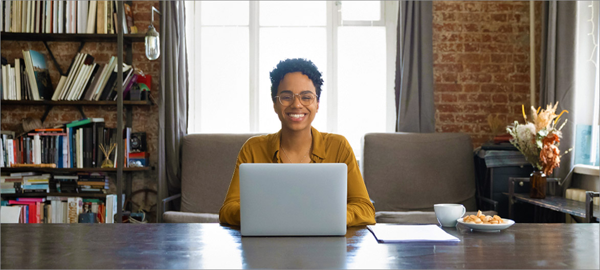 Picture. An employee working on their laptop smiling.