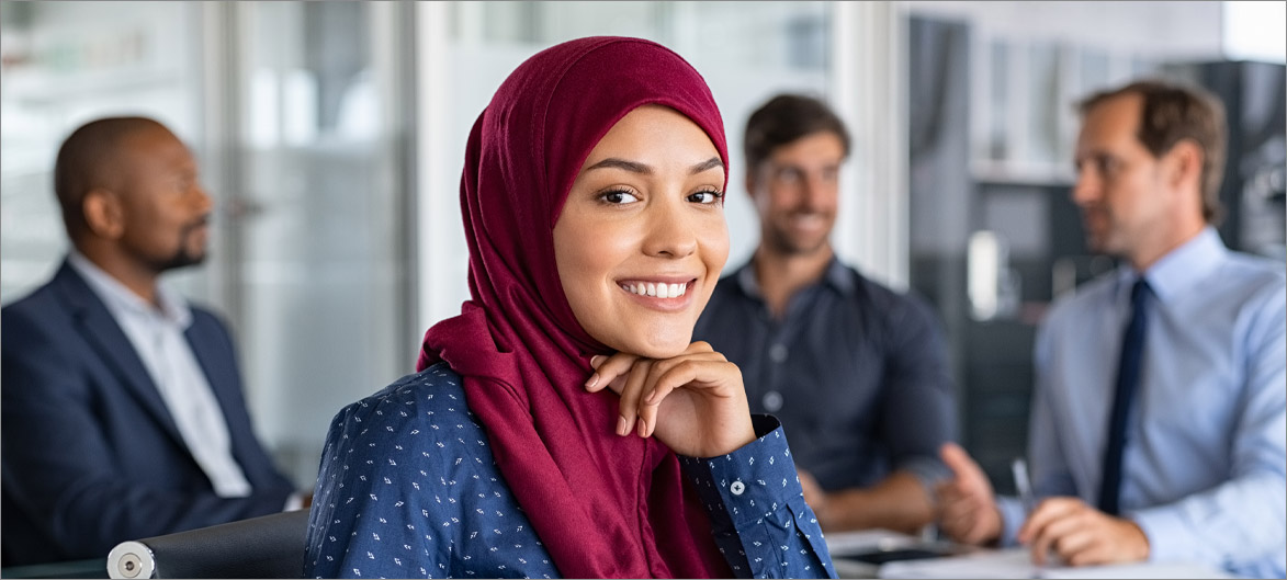 Picture. An employee sitting at a table smiling.